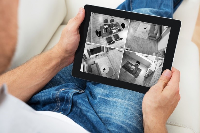 Man watching his home security cameras on the SecureNet app from his Tablet
